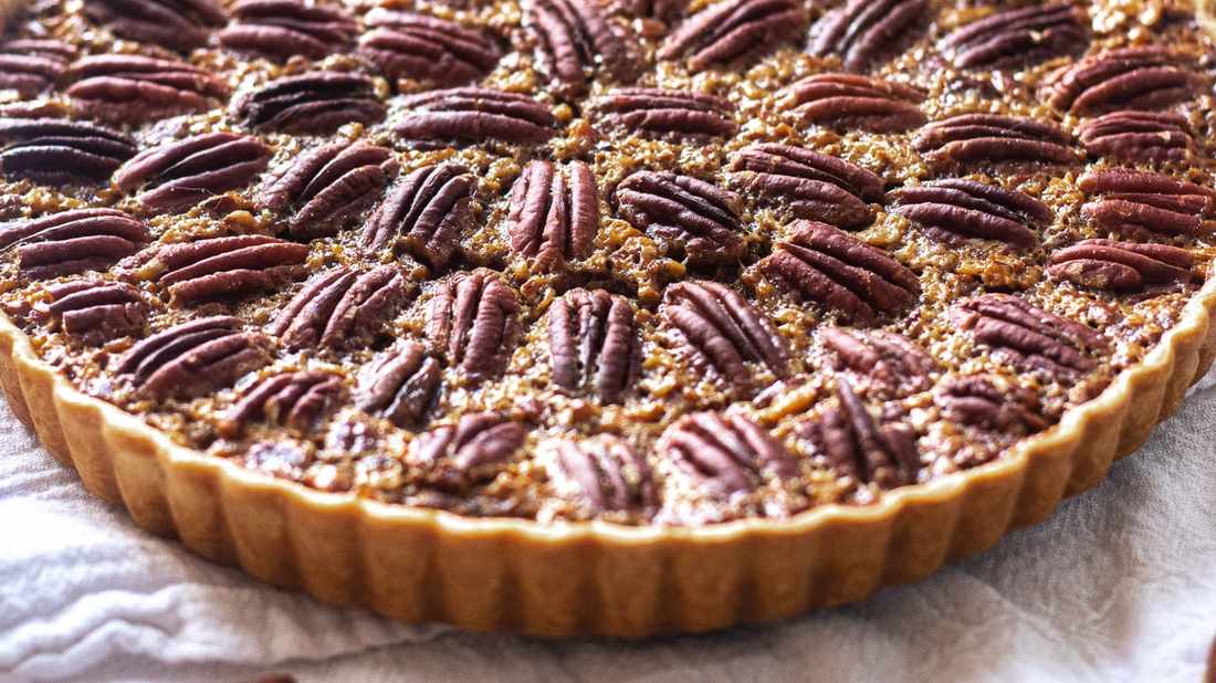 Golden classic pecan pie slice showcasing toasted pecans and vanilla caramel filling on flaky crust