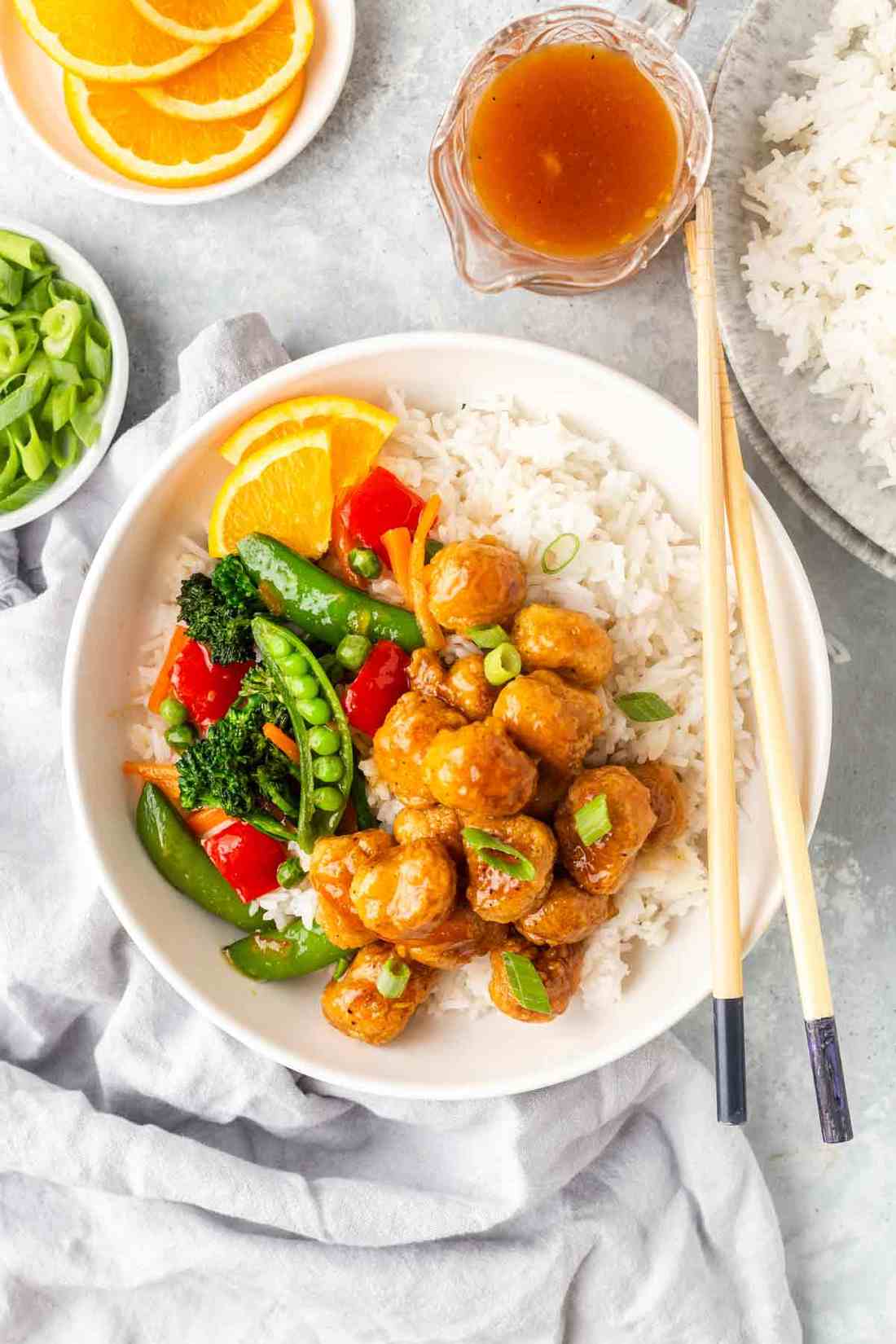 Orange‑glazed skinny chicken over brown rice with fresh orange slices and cilantro garnish