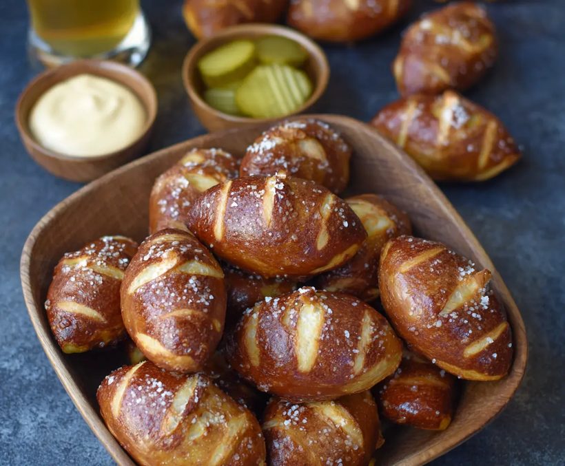 Football‑shaped soft pretzel bites with golden crust, sea salt, and a side of cheese dip