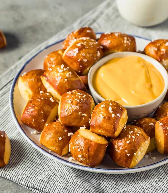 Soft pretzel bites served with a thick cheese dip and a sprinkle of paprika