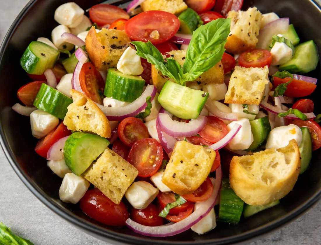 Classic summer panzanella with crusty bread cubes, ripe tomatoes, basil, mozzarella, olive oil