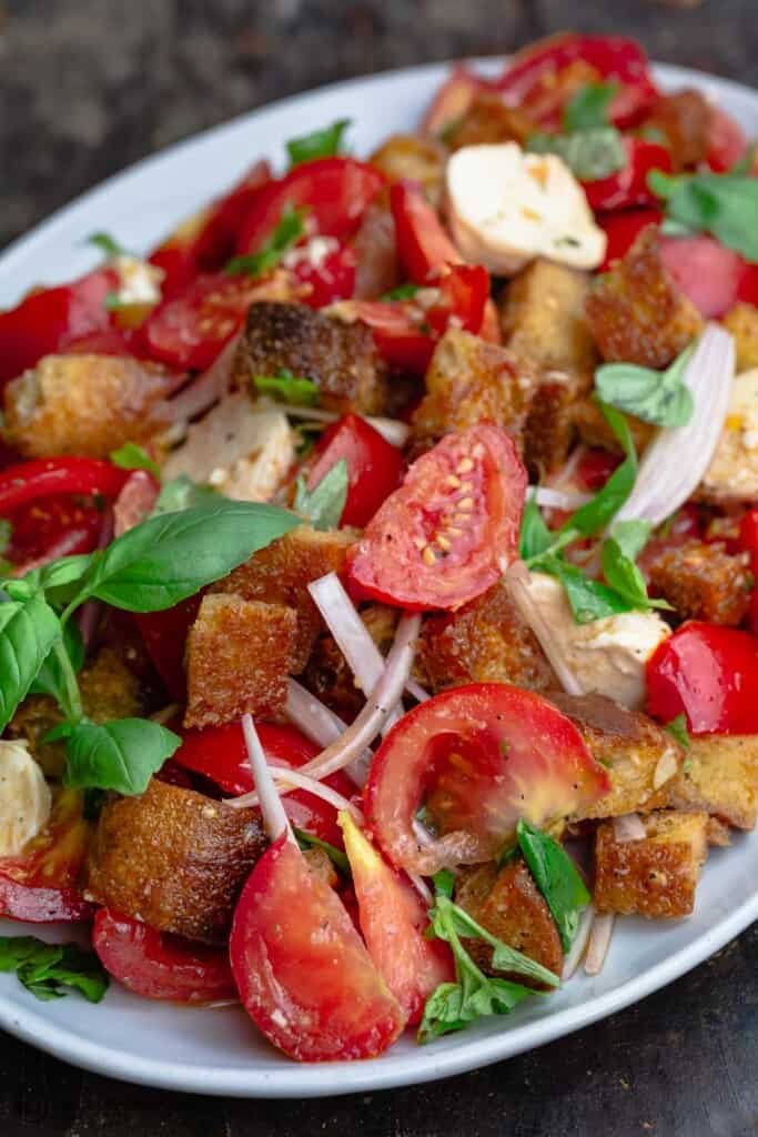 Classic summer panzanella with crusty bread cubes, ripe tomatoes, basil, mozzarella, olive oil