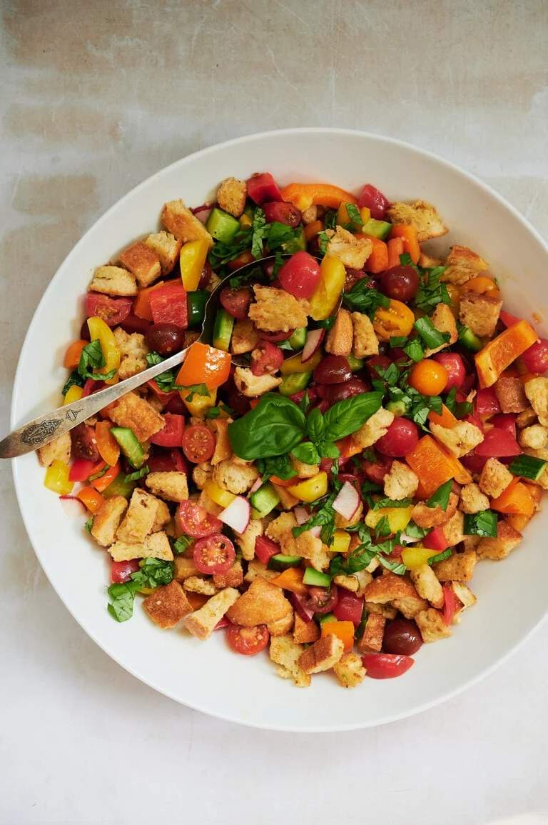 Classic summer panzanella salad with crusty bread cubes, ripe tomatoes, basil, mozzarella, olive oil