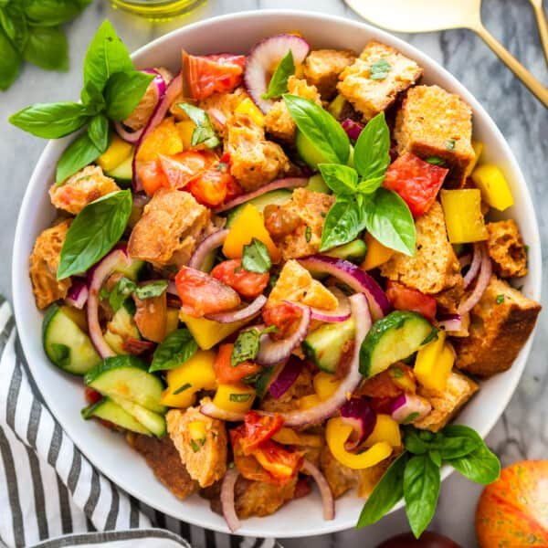 Classic summer panzanella salad with crusty bread cubes, ripe tomatoes, basil, mozzarella, olive oil
