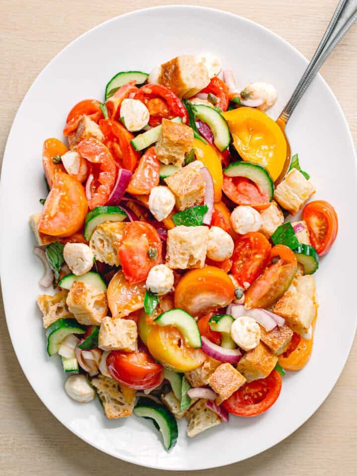 Classic summer panzanella salad featuring crusty bread cubes, ripe tomatoes, basil, mozzarella, olive oil