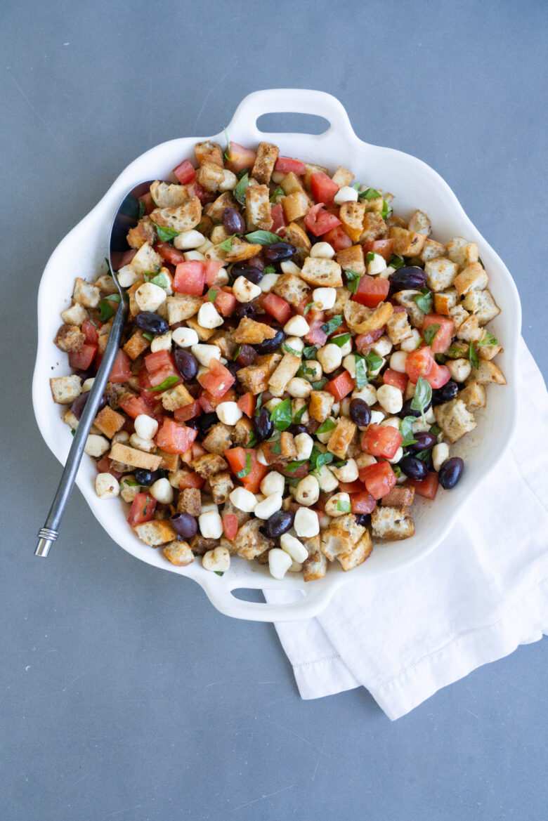 Classic summer panzanella salad with crusty bread cubes, ripe tomatoes, basil, mozzarella, olive oil