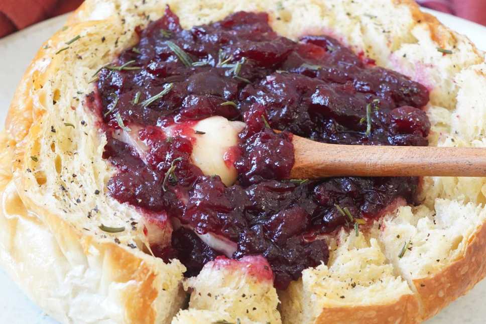 Hollowed round bread filled with melted brie, cranberry sauce, and toasted walnuts