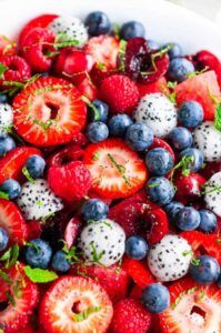 Colorful bowl of mixed berries, pomegranate seeds, and orange segments tossed in honey‑lime dressing