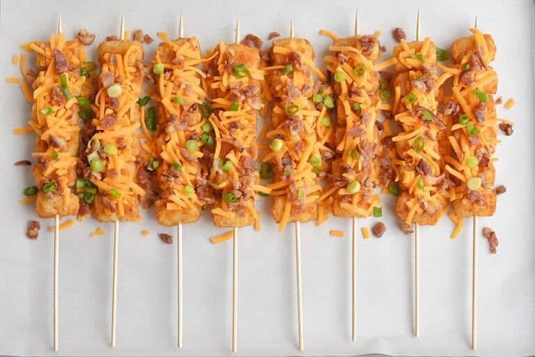 Golden tater tots threaded on skewers with melted cheese, bacon, and chives